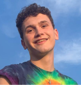 Man in a tie-dyed shirt in front of a blue sky. 