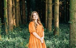 Woman in orange dress in front of a forrest
