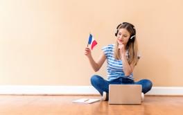 Woman holding French flag and looking at laptop