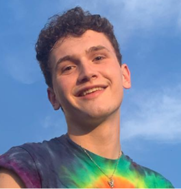 Man in a tie-dyed shirt in front of a blue sky.
