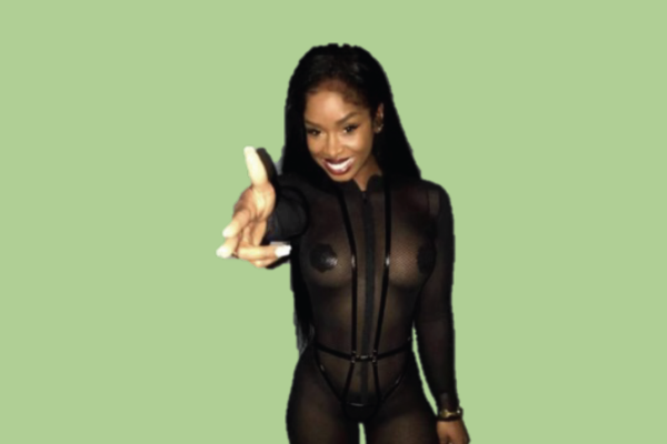 Woman wearing black outfit on light green background pointing